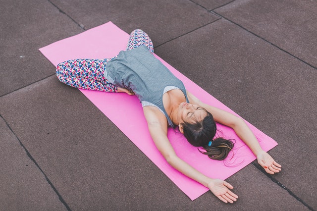 woman-lying-on-pink-yoga-mat-374686
